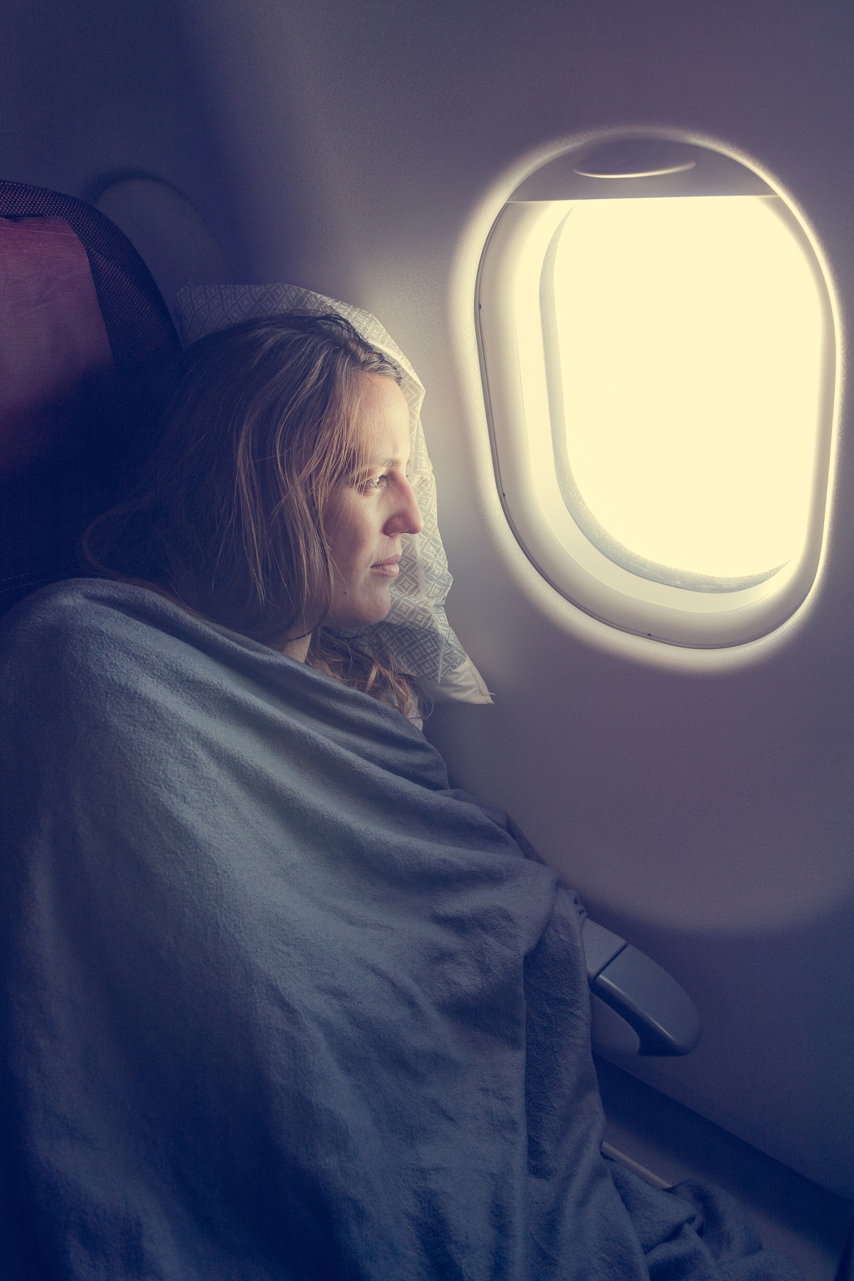 Une femme utilisant une couverture en avion