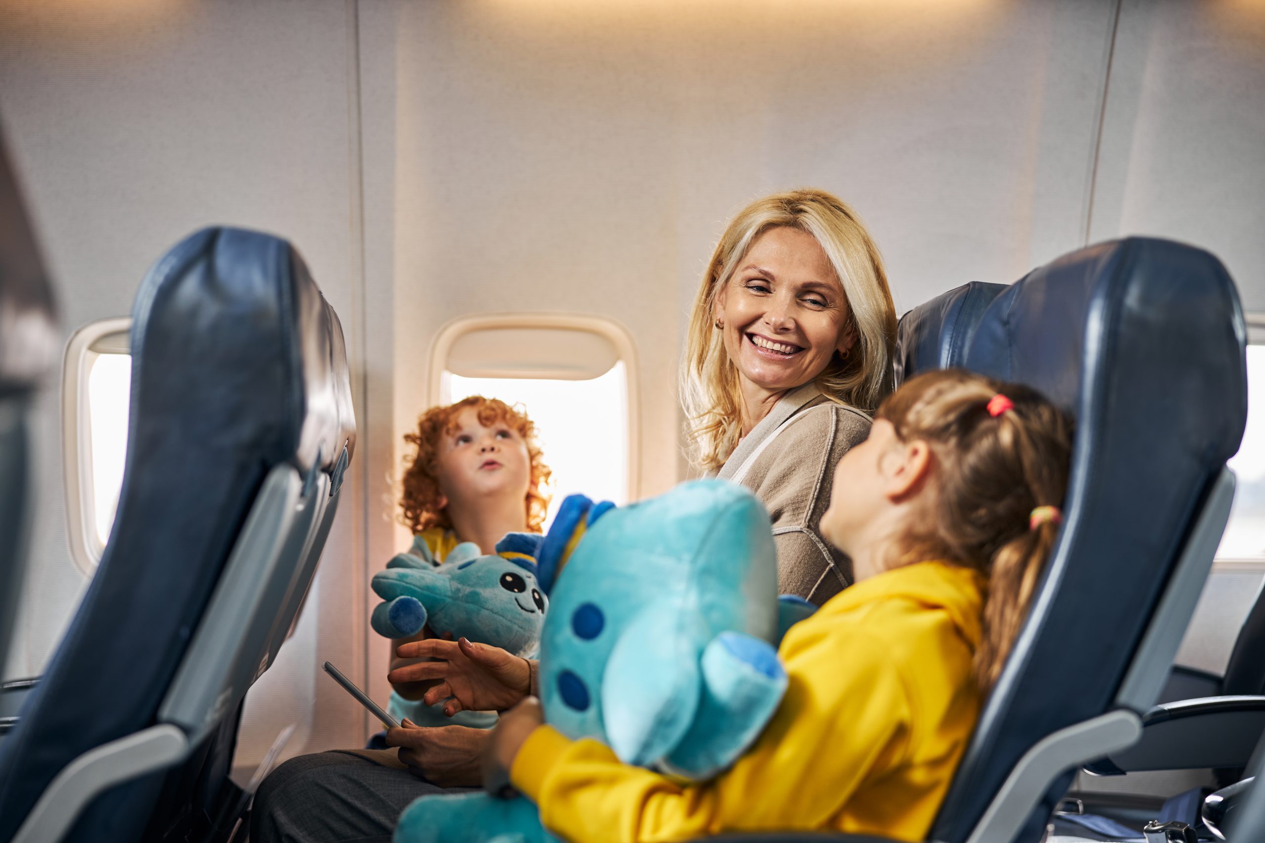 Waist-up photo of a female giving a cheerful look at her child holding a blue soft toy